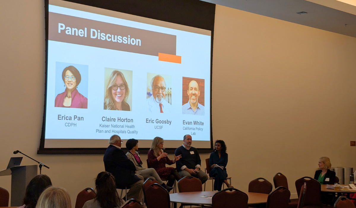 Photo from CPR3 symposium, shows four panelists with their photos displayed on a slide behind them
